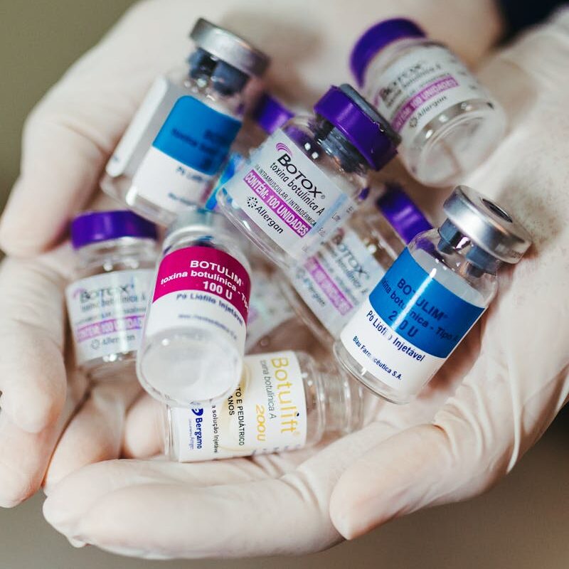 Close-up of gloved hands holding botulinum toxin vials in a laboratory, ideal for medical themes.